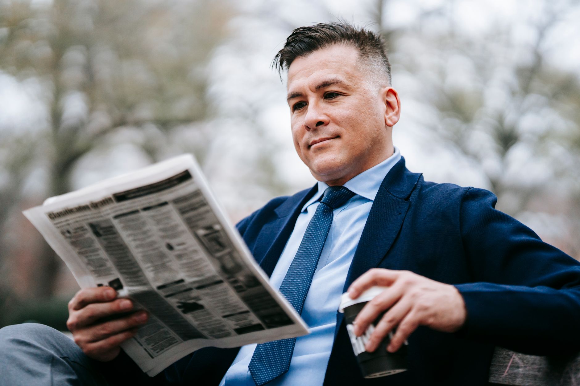 Stylish man in formal wear enjoys a drink while reading a newspaper outside. — Die besten Tischspiele im Rich Royal Casino: E