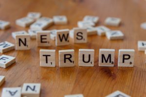 Wooden letter tiles spell 'NEWS' and 'TRUMP' on a wooden table, relating to political discourse. — GDF Casino: Ein Highlight
