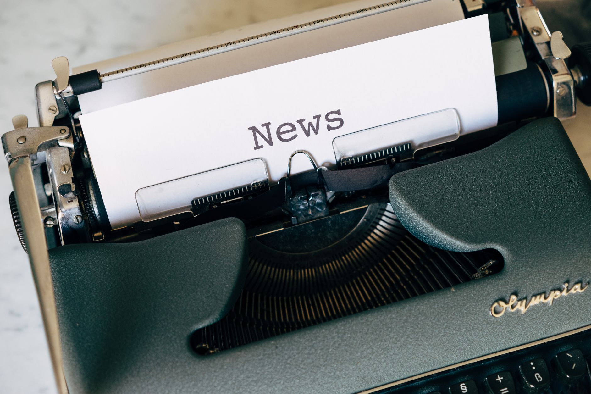 Close-up of a vintage Olympia typewriter with paper reading 'news'. Perfect for classic journalism themes. — Kommende Spiele