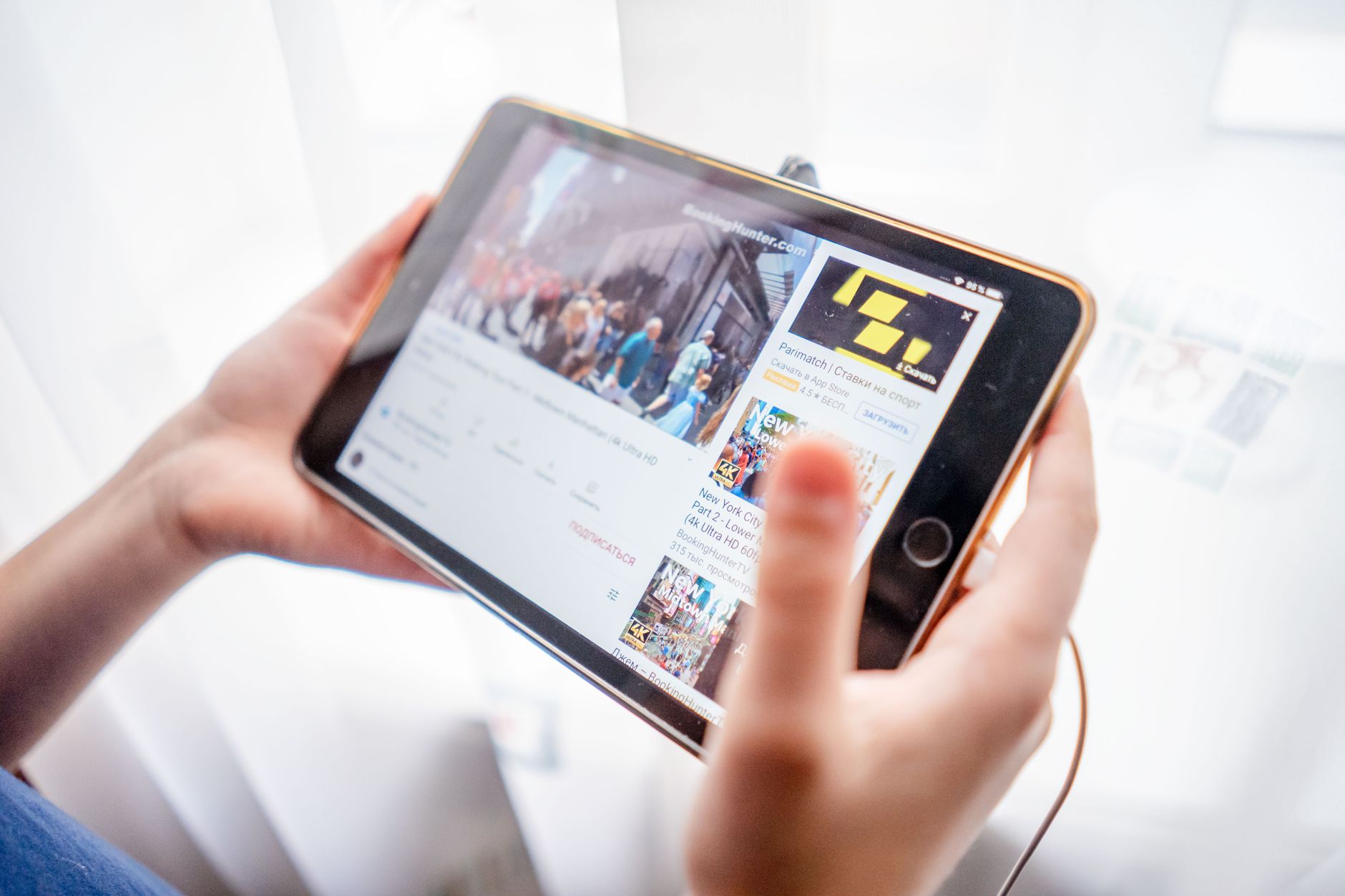 Close-up of hands holding a tablet device browsing online content indoors. — The Founding of YouTube A Short History