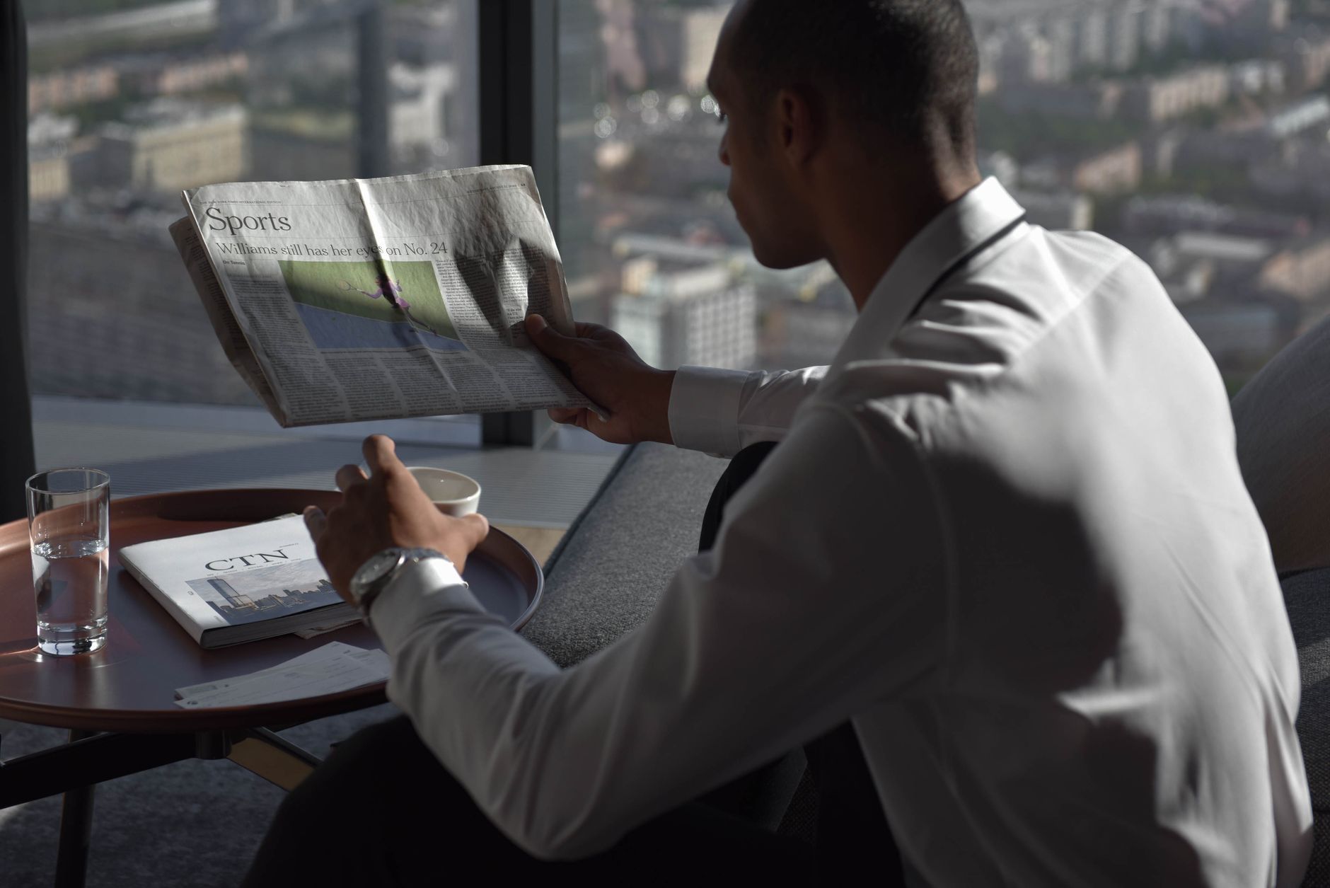Businessman in office reading sports section, enjoying coffee with city view. — Wie verlockend sind die Promotionen im Only S
